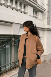 a lady in a brown woolen jacket and a pair of jeans